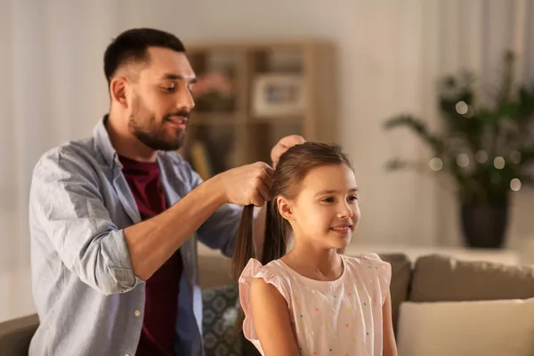 Dad braids his daughter’s hair on the couch—an everyday “Girl Dad” moment at home.