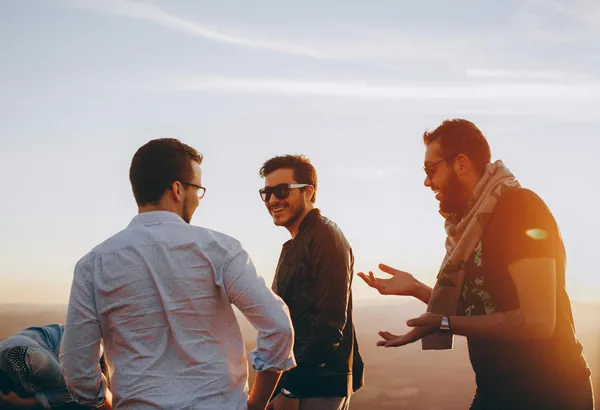 Group of male friends laughing together outdoors during sunset in Brazil.