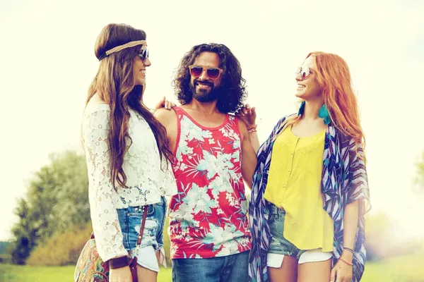 Nature, summer, youth culture and people concept - smiling young hippie friends in sunglasses talking outdoors