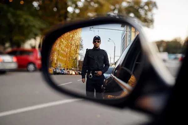 Photo police officer, view through car rear view mirror
