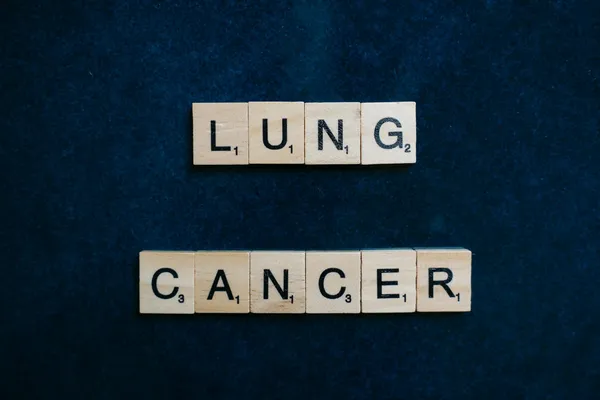 Scrabble tiles spelling lung cancer on dark background symbolizing awareness.