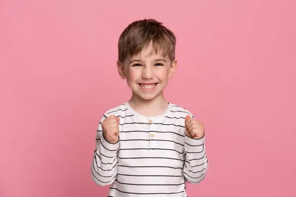 Smiley little boy isolated on pink
