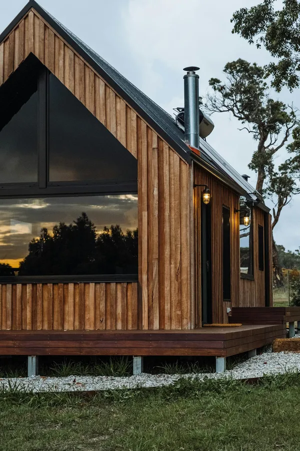 Stylish wooden cabin surrounded by nature during sunset, showcasing modern architecture.