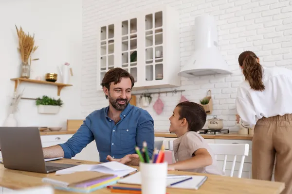 Father planning family finances and life insurance while working at the kitchen table with his child