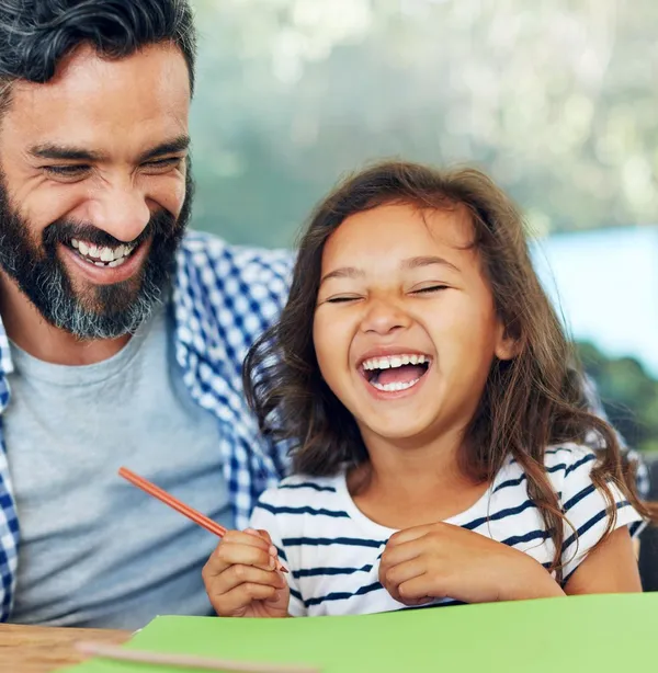 Modern dad smiling with his daughter during a homework moment, reflecting the quiet pressure fathers often carry