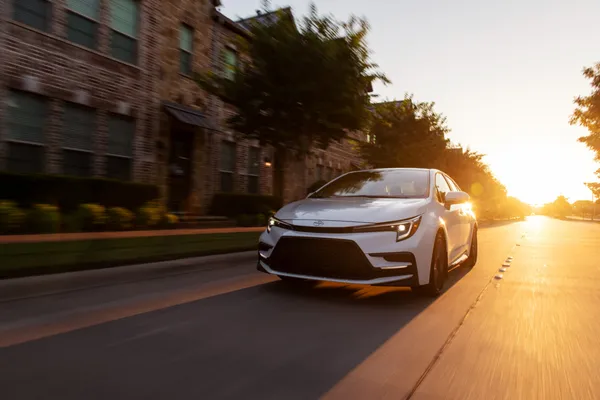 2026 Toyota Corolla Cross XLE AWD driving on city road during sunset exterior view