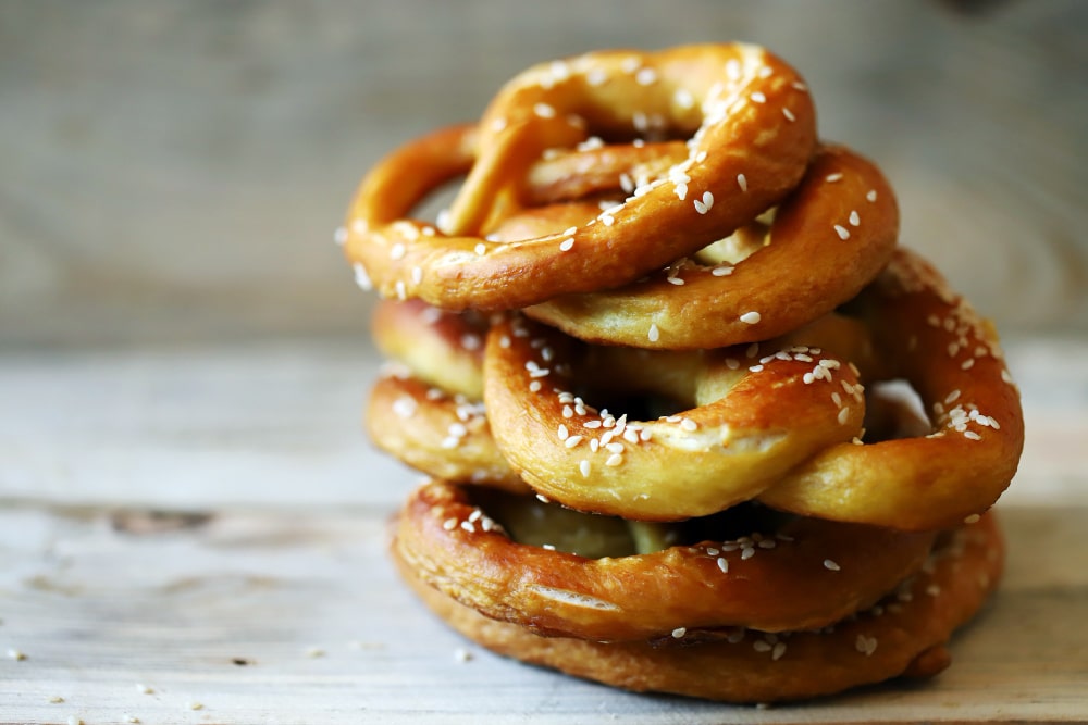Fresh homemade pretzels stacked on a wooden surface.
