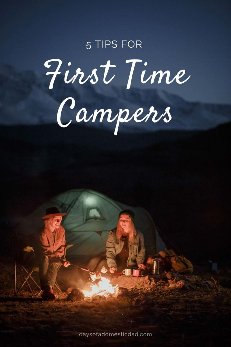 Two young adults camping in the dark, camp fire