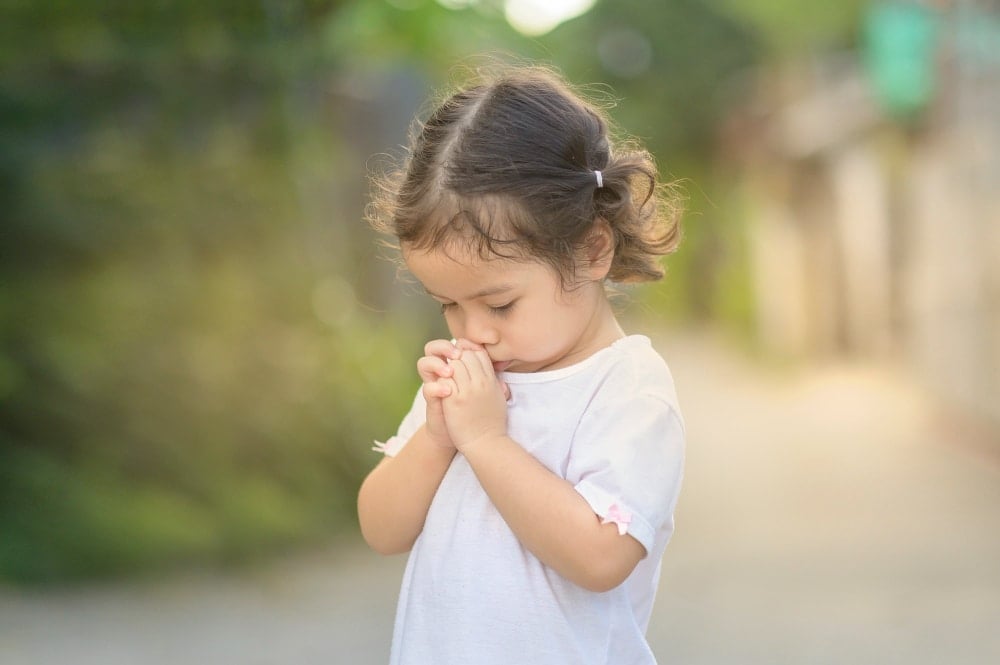 Cute asian little girl closed her eyes and praying in the morning. little asian girl hand praying,hands folded in prayer concept for faith,spirituality and religion.