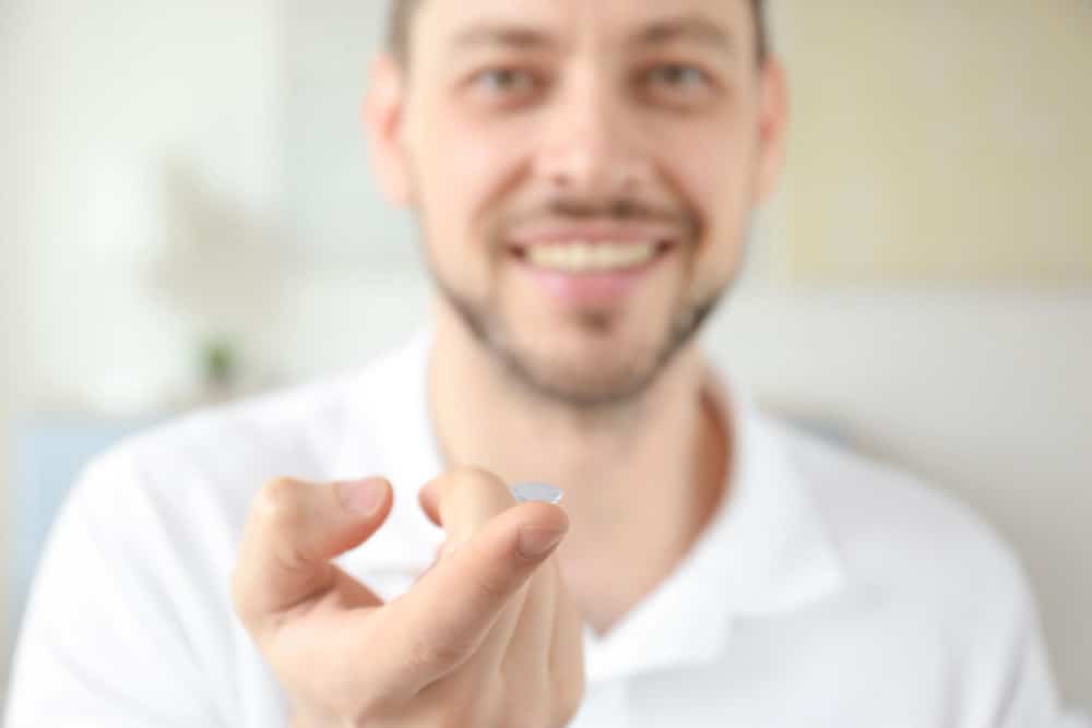 Hand of young man with contact lens, closeup