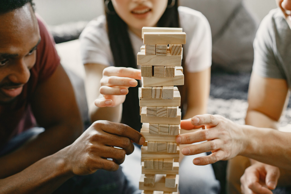 Free photo african boy and asian couple playing jenga play board game in a free time focus on a game