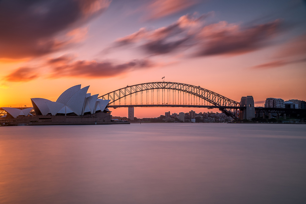 Free photo beautiful shot of the sydney harbor bridge with a light pink and blue sky