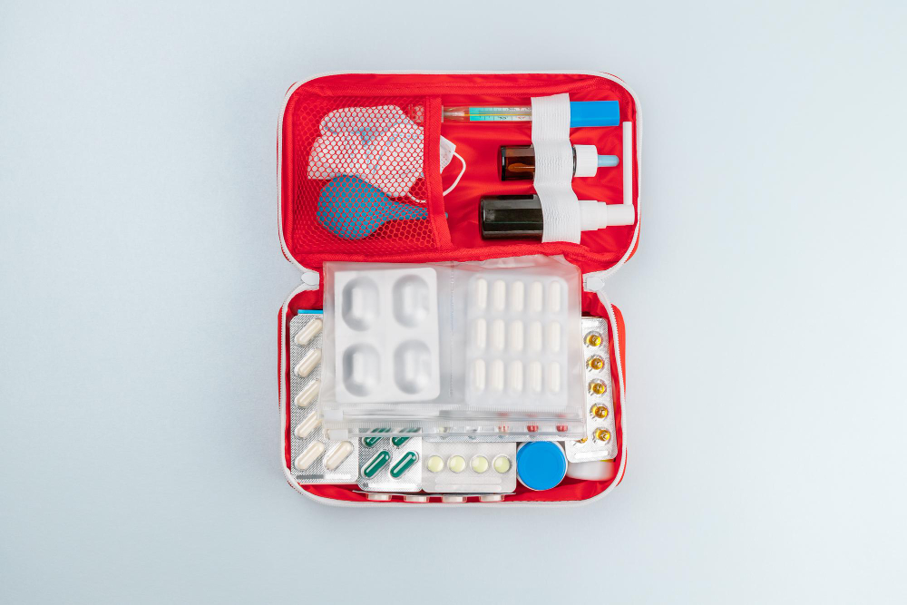 Open red home first aid kit box for medicines vitamins medicaments pills thermometer flat lay