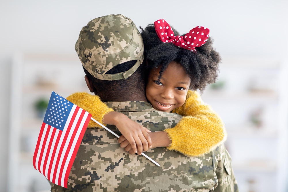 Cute little black girl holding american flag and embracing soldier dad