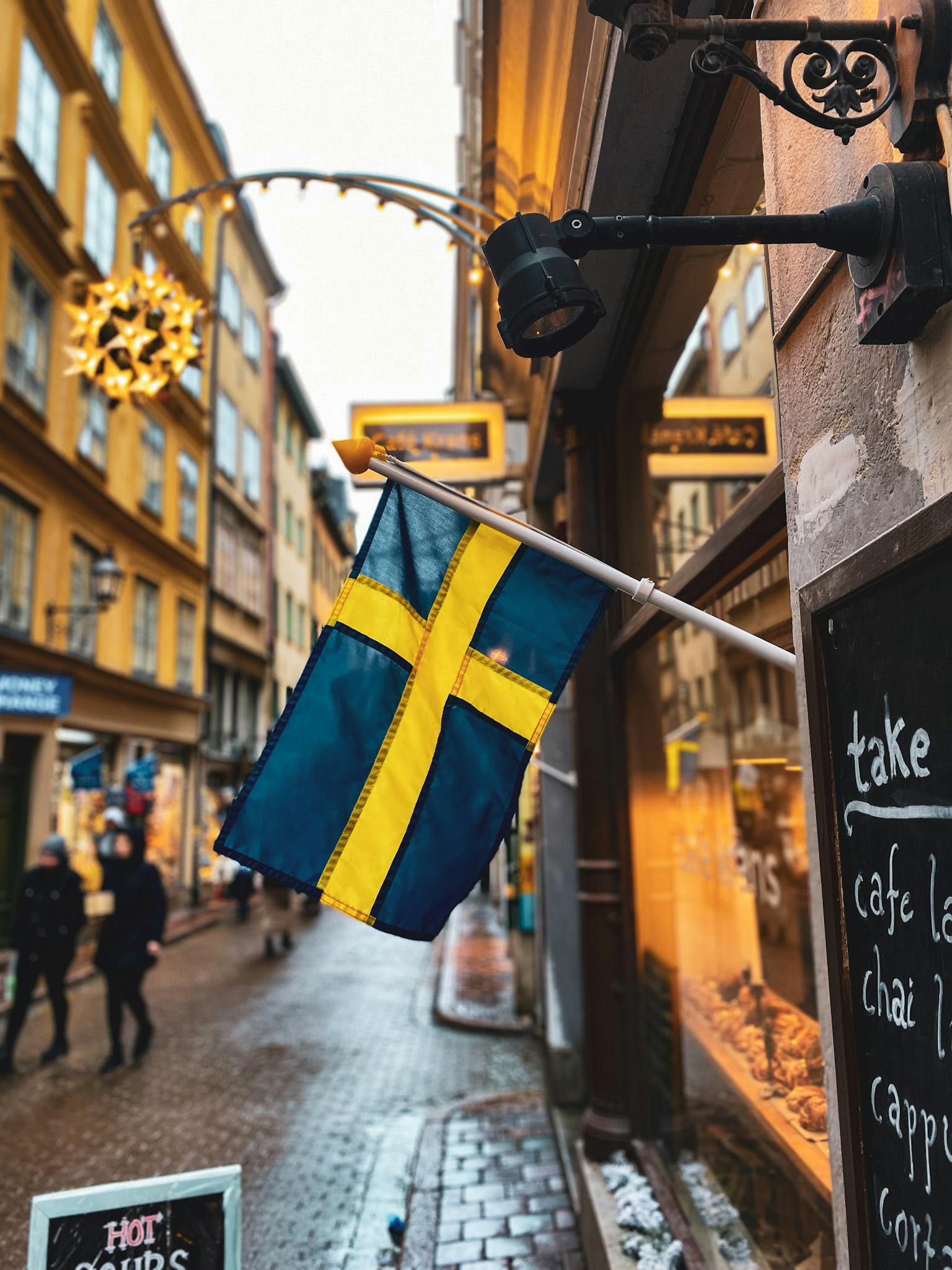 A vibrant street scene in Stockholm featuring a Swedish flag and festive decorations.