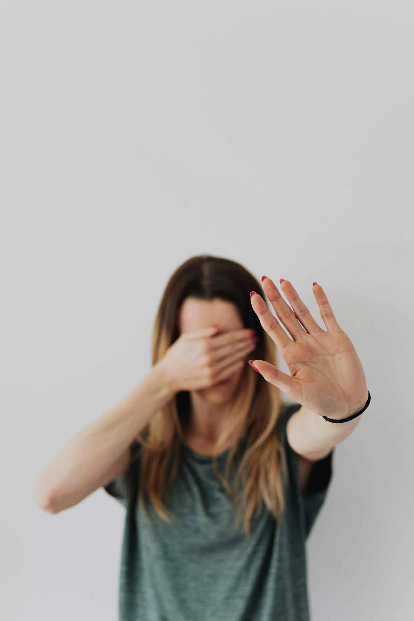 A woman with long hair gestures to stop with one hand, conveying a message of prevention or refusal.